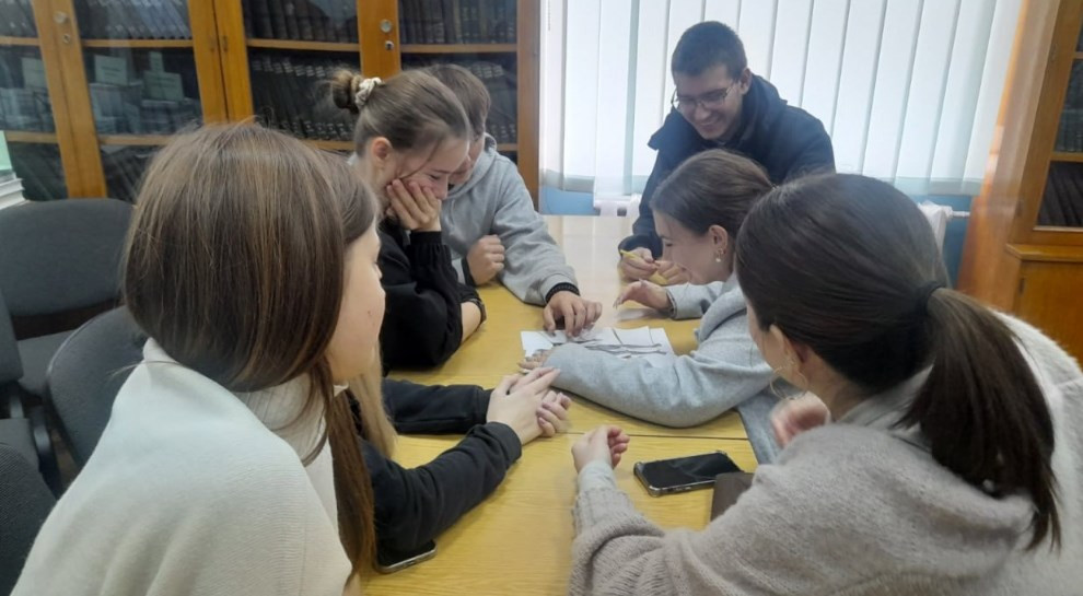 Студенти за столом працюють в науковій бібліотеці збирають пазли